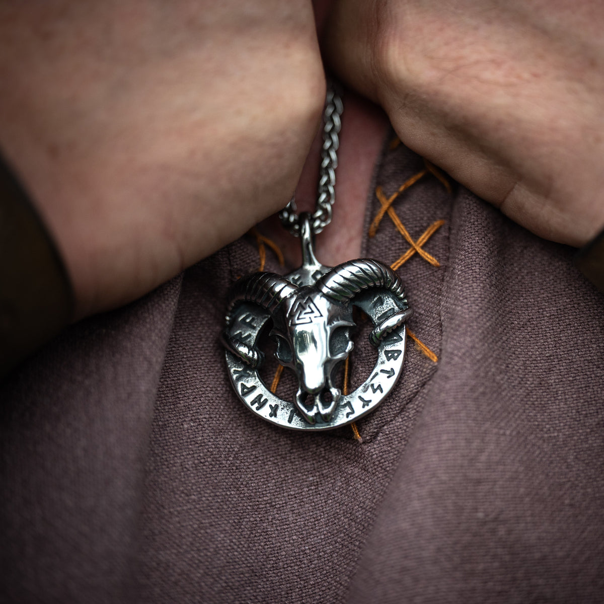 Close-up of the Heidrun Necklace featuring a silver-tone horned goat pendant with Norse-inspired detailing, worn over a brown Viking tunic.