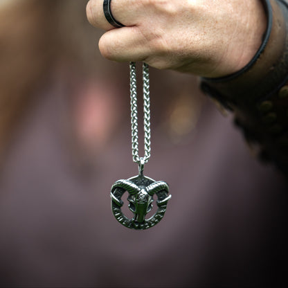 Viking-inspired model holding the Heidrun Necklace by its chain, displaying the silver-tone horned pendant against a blurred background.