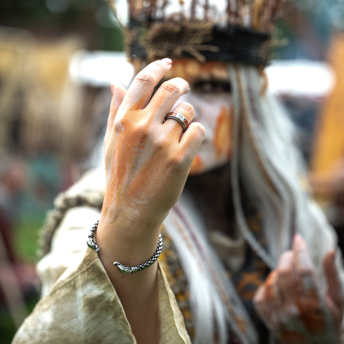Jörmungandr Viking serpent bracelet worn on a model's wrist, with a silver ring and Nordic-inspired costume.